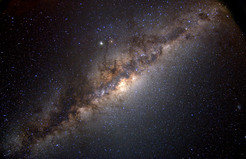 View of the Milky Way in the southern sky. One can see the Galactic disk and the somewhat thicker central region, the bulge; the irregular appearance is due to absorption from intervening dust. The Galactic centre itself is hidden by dense clouds of gas and dust.