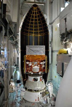 This photograph shows the two instruments of the Fermi Gamma-ray Space Telescope a few days before launch. The Gamma-ray Burst Monitor (GBM) is in the lower part of the satellite, 7 of its 14 crystal detectors are visible on the front (wrapped in white). The GBM bus, wrapped in gold-coated foil, is mounted on the spacecraft on top of the Delta2 rocket. On the top, Fermi’s other instrument, the Large Area Telescope (LAT), is visible, wrapped in silver foil.