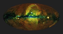 Energiereiches Universum: Die erste vollständige eRosita-Himmelsdurchmusterung lief über einen Zeitraum von sechs Monaten. Hierbei rotierte das Teleskop kontinuierlich, was eine gleichmäßige Belichtung von etwa 150 bis 200 Sekunden über den größten Teil des Himmels lieferte; die Pole der Ekliptik wurden öfter besucht, wodurch hier die Aufnahmen tiefer sind. Um dieses Bild zu erzeugen, bei dem das gesamte Firmament auf eine Ellipse projiziert wird (Aitoff-Projektion) mit dem Zentrum der Milchstraße in der Mitte und der Scheibe der Milchstraße in der Horizontalen, wurden die Photonen entsprechend ihrer Energie farblich kodiert (rot für Energien 0,3 bis 0,6 keV, grün für 0,6 bis 1 keV, blau für 1 bis 2,3 keV).