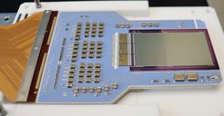 Detector module with frame store PNCCD chip (56 mm x 37 mm) and 3 custom CAMEX analogue signal processor ASICs for readout. The silicon chips are mounted on a ceramic board (blue) with mechanical and thermal interface at the bottom. A 152-pin connector (not shown) at the end of the flexible lead (brown) serves as electrical interface.